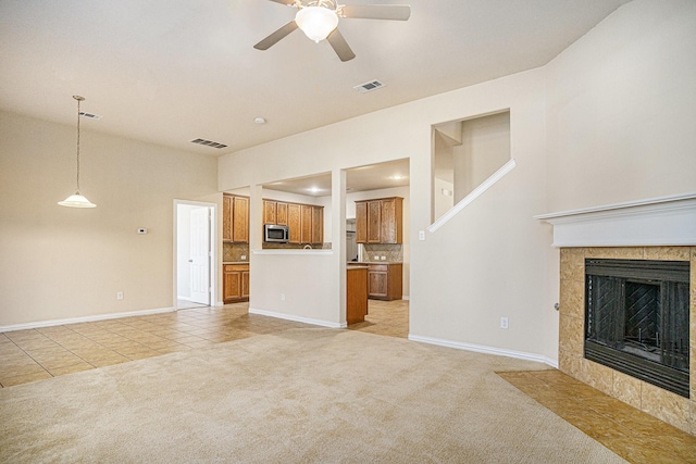 unfurnished living room with a fireplace, light colored carpet, and ceiling fan