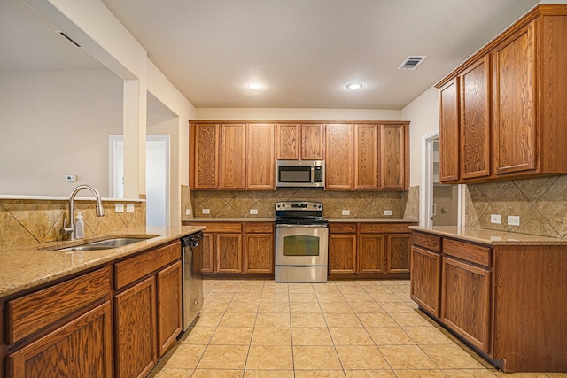 kitchen with sink, light tile patterned floors, stainless steel appliances, tasteful backsplash, and light stone countertops