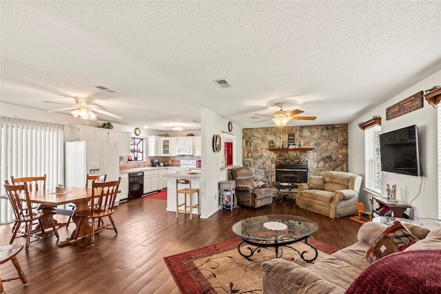 living room with ceiling fan, dark hardwood / wood-style flooring, a fireplace, and a textured ceiling