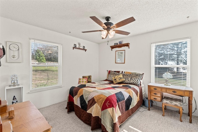 carpeted bedroom featuring multiple windows, ceiling fan, and a textured ceiling