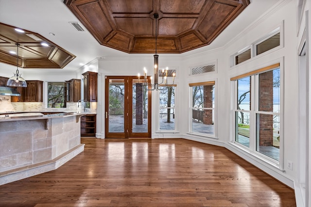 unfurnished dining area featuring crown molding, dark hardwood / wood-style flooring, and an inviting chandelier