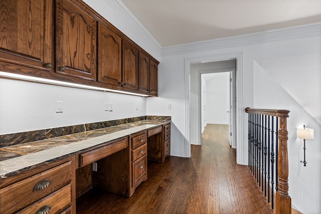 kitchen featuring dark wood-type flooring, crown molding, built in desk, dark brown cabinets, and dishwasher