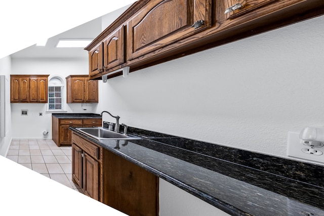 kitchen featuring sink, light tile patterned floors, and dark stone counters