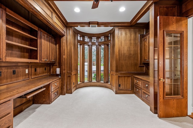 carpeted home office with crown molding, built in desk, and wood walls