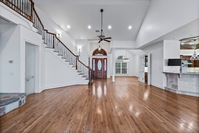 unfurnished living room with hardwood / wood-style flooring, ceiling fan, and high vaulted ceiling