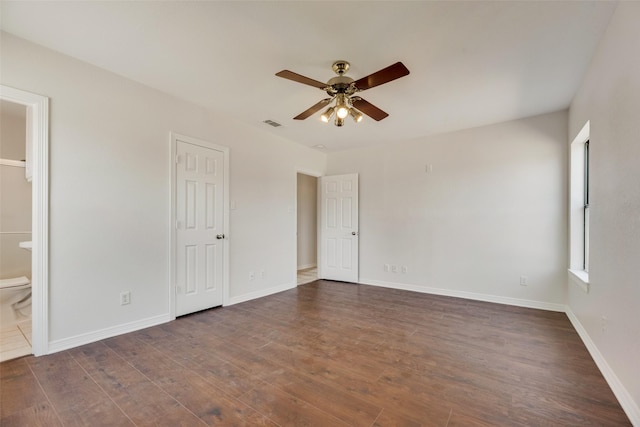 unfurnished bedroom featuring ceiling fan, dark hardwood / wood-style flooring, and ensuite bath