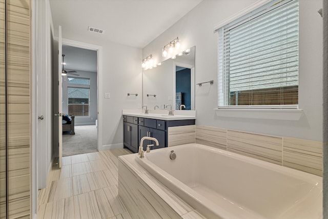 bathroom featuring vanity, tiled tub, and ceiling fan