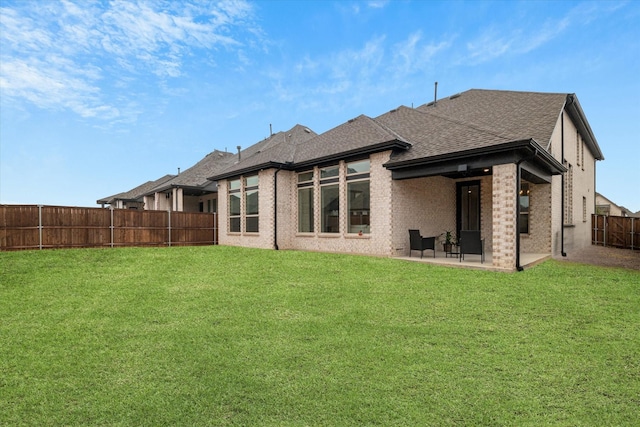 rear view of property with a lawn and a patio