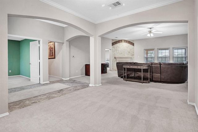 unfurnished living room with a large fireplace, light carpet, crown molding, and ceiling fan