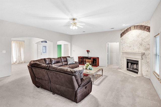 carpeted living room with vaulted ceiling, ceiling fan, and a premium fireplace