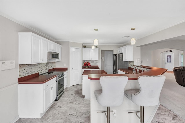 kitchen featuring white cabinetry, stainless steel appliances, crown molding, a breakfast bar area, and pendant lighting