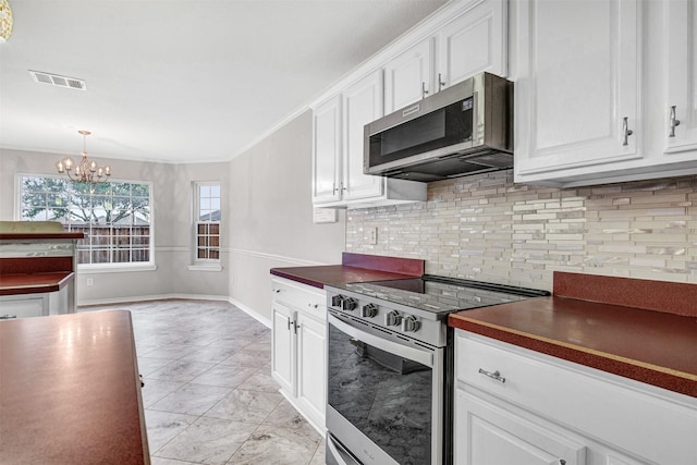 kitchen with white cabinets, appliances with stainless steel finishes, crown molding, and backsplash