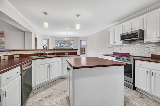 kitchen featuring appliances with stainless steel finishes, white cabinets, pendant lighting, a center island, and sink