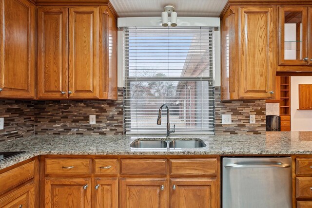kitchen with a sink, tasteful backsplash, stainless steel dishwasher, brown cabinetry, and glass insert cabinets