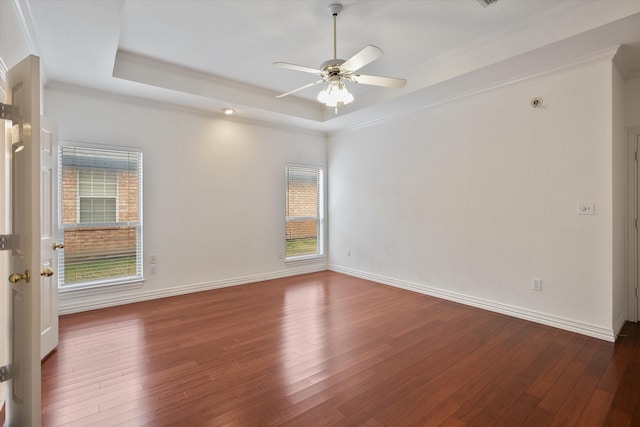 empty room with ceiling fan, ornamental molding, a tray ceiling, and dark hardwood / wood-style flooring