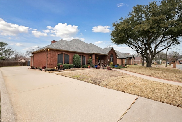 view of front of house with brick siding, concrete driveway, and a chimney