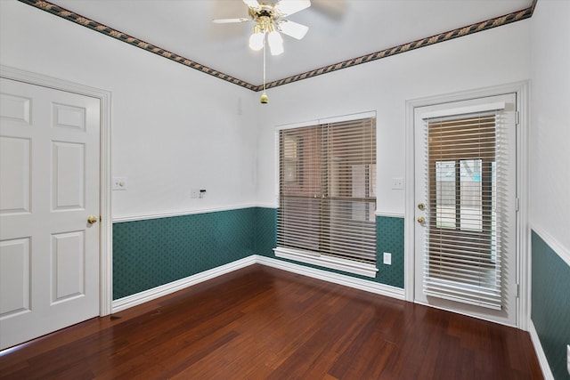 empty room featuring a wainscoted wall, wood finished floors, and a ceiling fan