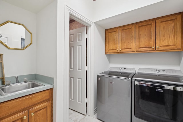 clothes washing area featuring cabinets, washer and clothes dryer, sink, and light tile patterned floors