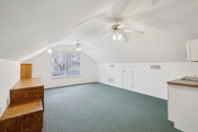 bonus room featuring dark colored carpet, lofted ceiling, sink, and ceiling fan