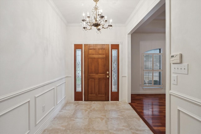 entryway with crown molding and an inviting chandelier