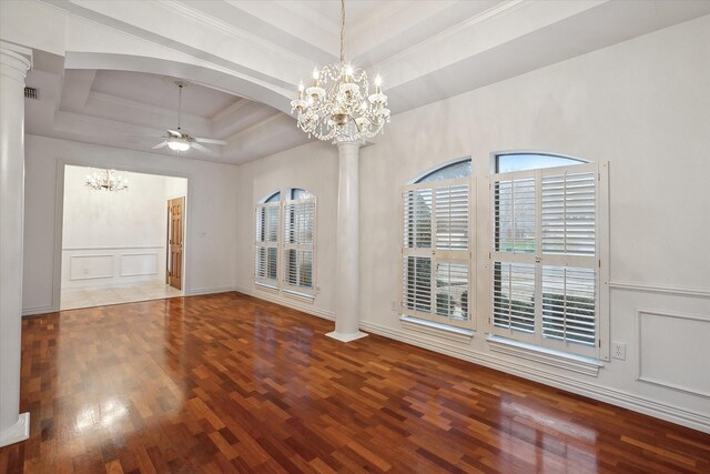 interior space with dark wood-type flooring, decorative columns, a tray ceiling, ornamental molding, and ceiling fan with notable chandelier