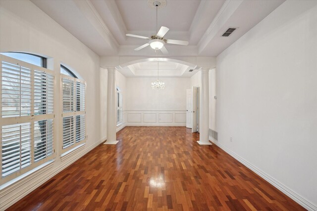 unfurnished room with ornate columns, ceiling fan with notable chandelier, a tray ceiling, crown molding, and dark wood-type flooring