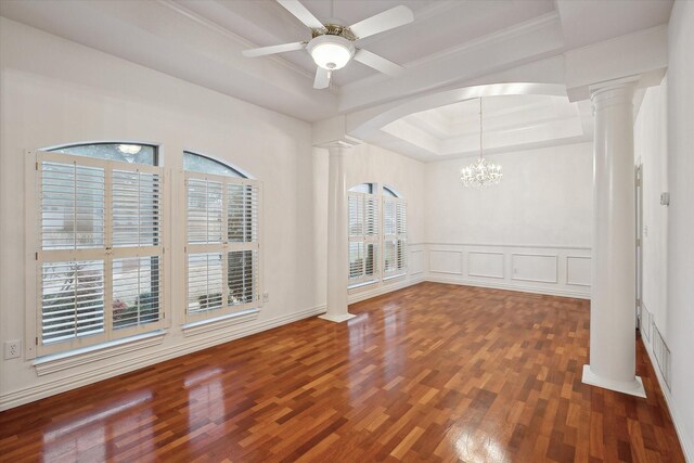 empty room featuring ceiling fan with notable chandelier, decorative columns, wood-type flooring, a raised ceiling, and a healthy amount of sunlight