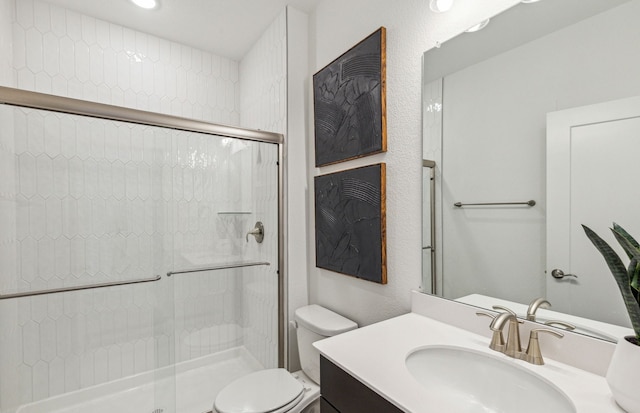 bathroom with vanity, a shower with shower door, and toilet