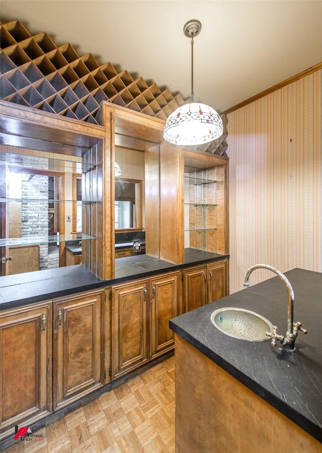 kitchen with hanging light fixtures, light parquet floors, sink, and dark stone counters