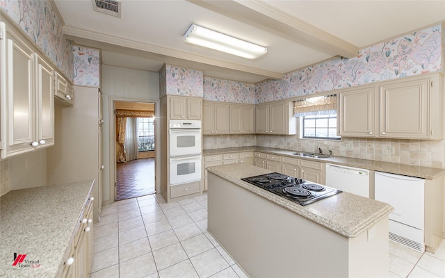 kitchen featuring a kitchen island, sink, white appliances, beam ceiling, and cream cabinetry