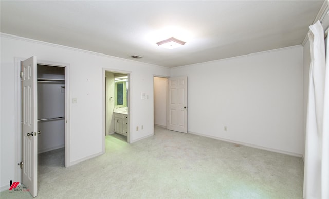 unfurnished bedroom with a walk in closet, ornamental molding, light colored carpet, and a closet