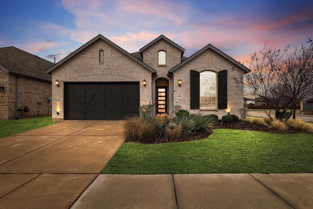 french country home with a garage and a lawn