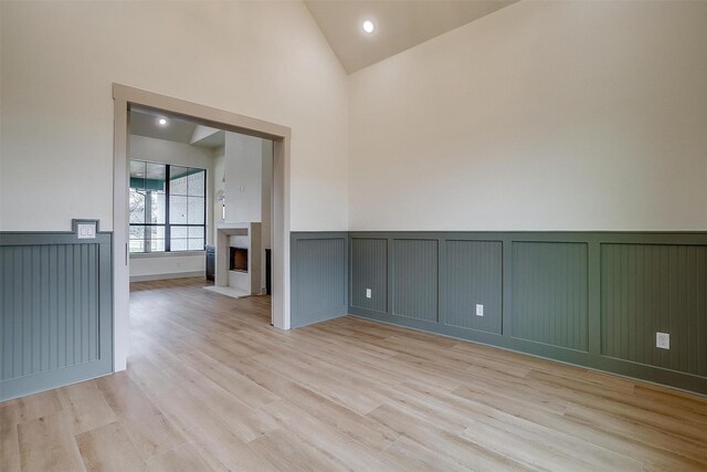 empty room featuring high vaulted ceiling and light wood-type flooring