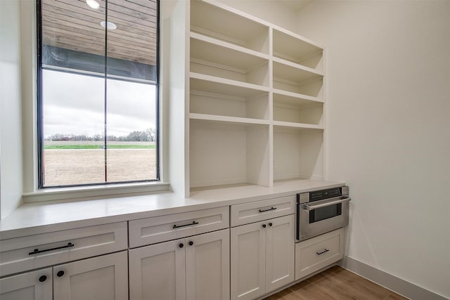 kitchen with light hardwood / wood-style flooring, oven, and white cabinets