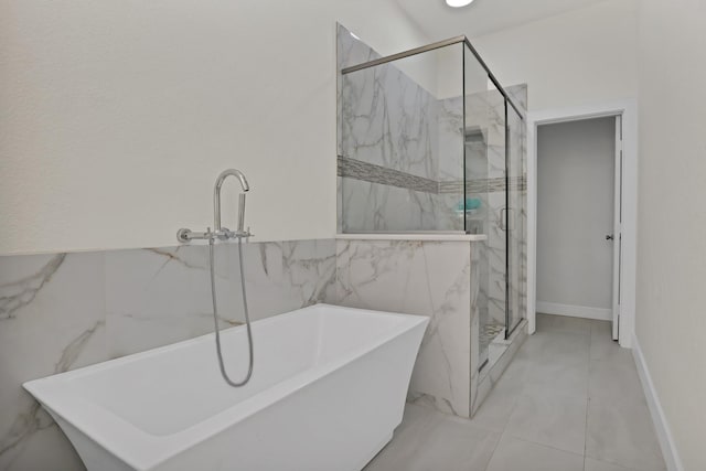 full bath featuring a freestanding tub, a marble finish shower, marble finish floor, and tile walls