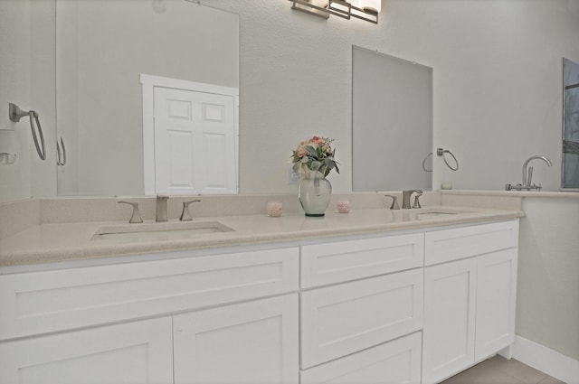 full bathroom with double vanity, a sink, and baseboards