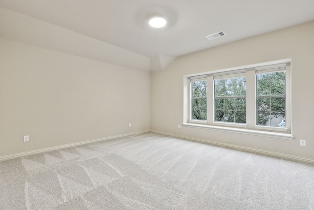 unfurnished room with light colored carpet and lofted ceiling