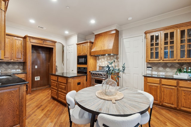 kitchen featuring light hardwood / wood-style floors, black appliances, custom range hood, and a kitchen island