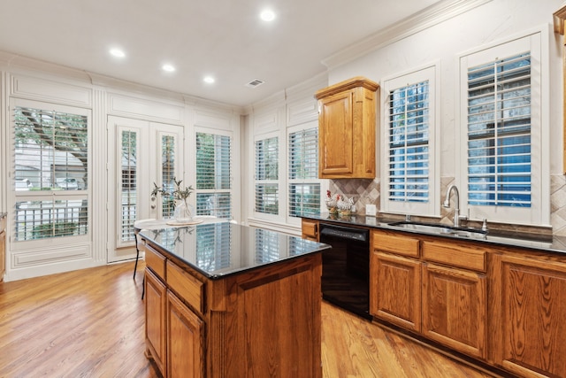 kitchen with a kitchen island, dishwasher, sink, ornamental molding, and light wood-type flooring