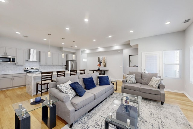 living room with baseboards, light wood-type flooring, visible vents, and recessed lighting