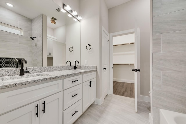 bathroom featuring vanity, toilet, and a tile shower