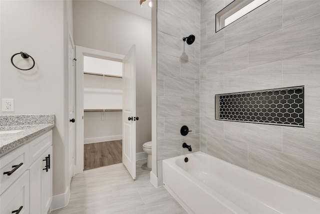 full bathroom with tiled shower / bath, vanity, and toilet