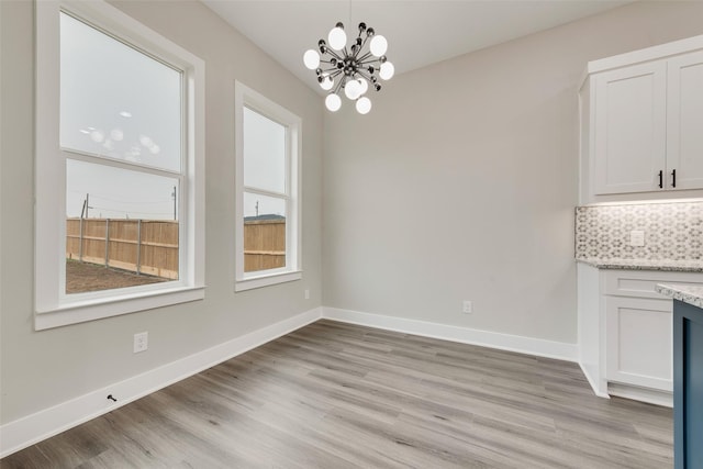 unfurnished dining area with a notable chandelier and light wood-type flooring