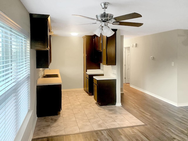 kitchen with dark brown cabinetry, ceiling fan, sink, and light wood-type flooring