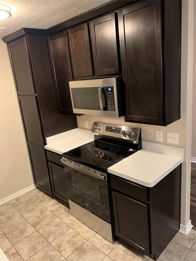 kitchen featuring light tile patterned flooring, dark brown cabinetry, and appliances with stainless steel finishes