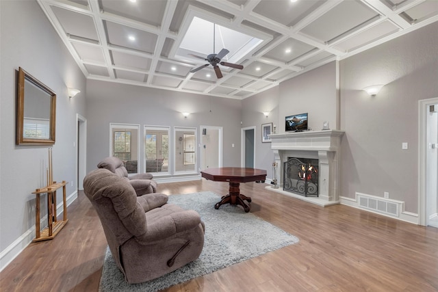 living room with coffered ceiling, wood-type flooring, ceiling fan, and a high ceiling