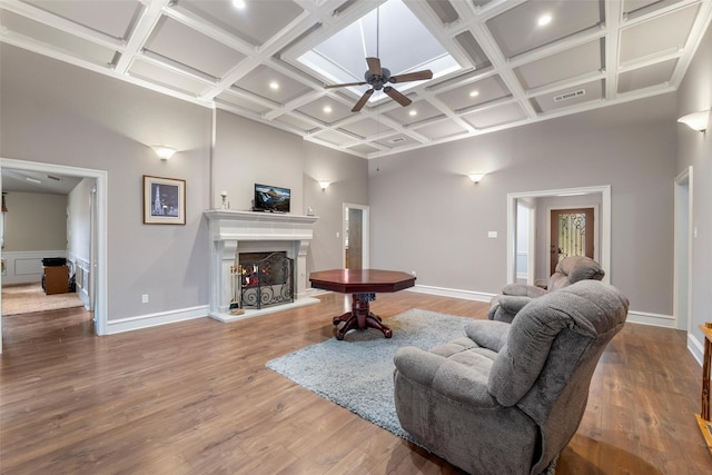 living room featuring coffered ceiling, hardwood / wood-style floors, and a high ceiling