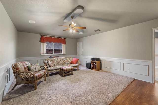 living room with ceiling fan, wood-type flooring, and a textured ceiling