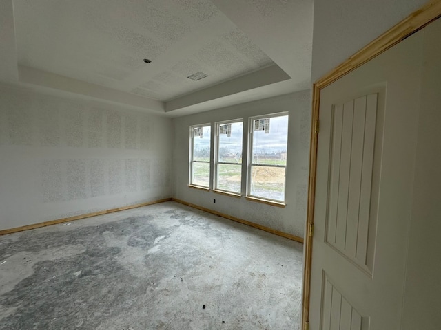 spare room featuring carpet flooring, a tray ceiling, and a textured ceiling