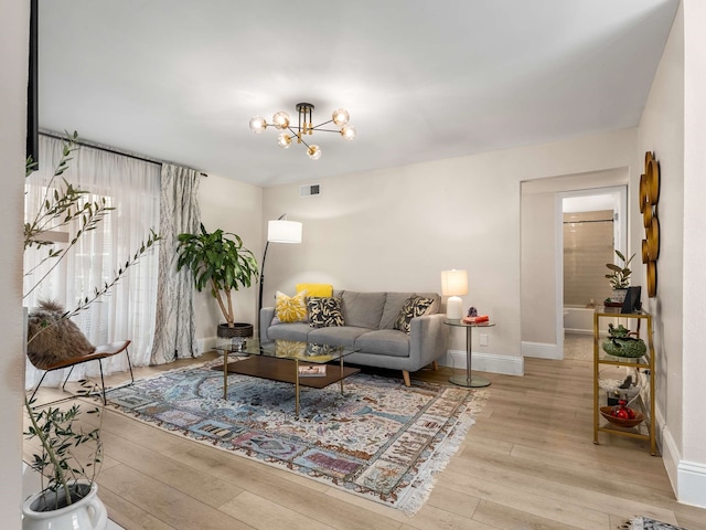 living room featuring a notable chandelier and light wood-type flooring